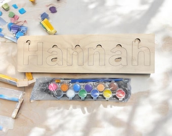 May include: A wooden sign with the name "Hannah" cut out, ready to be painted. The sign comes with a set of 12 watercolor paints and a paintbrush.