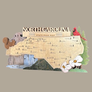 Puede incluir: Mapa de madera del Parque Estatal de Carolina del Norte con una ardilla, una cascada, un cardenal y flores de cornejo. El mapa es de color marrón claro con el contorno del estado y las ubicaciones de los parques. Las palabras "North Carolina State Park Map" están en la parte superior.