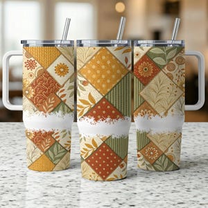 Puede incluir: Tres vasos de acero inoxidable con tapas y pajitas. Los vasos están decorados con un patrón de patchwork en tonos naranja, amarillo, verde y marrón.