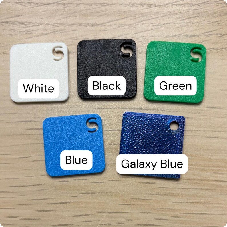 Puede incluir: Cinco muestras de color cuadradas en blanco, negro, verde, azul y azul galaxia. Cada muestra tiene una esquina redondeada y un agujero. Los colores est&aacute;n etiquetados con texto blanco sobre un fondo blanco: Blanco, Negro, Verde, Azul y Azul Galaxia.