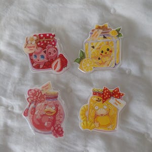 May include: Four clear acrylic pins featuring cartoon characters inside jars. The jars have different themes: strawberry, lemon, and two other designs. Each pin has a unique character and decorative elements like bows and flowers.