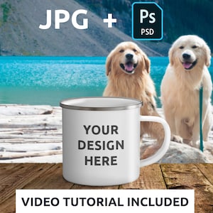 May include: White enamel camping mug with a silver rim. The mug has the text "YOUR DESIGN HERE" printed on it. The mug is sitting on a wooden surface in front of a lake with two golden retrievers.