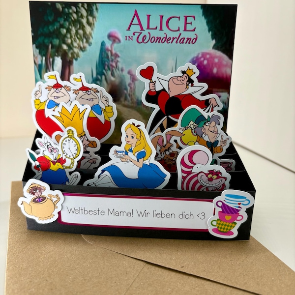 Peut inclure: Une carte pop-up avec des personnages d'"Alice au pays des merveilles". La carte comprend Alice, la Reine de Cœur, le Chapelier Fou et le Chat du Cheshire. Le texte "Alice in Wonderland" est visible.