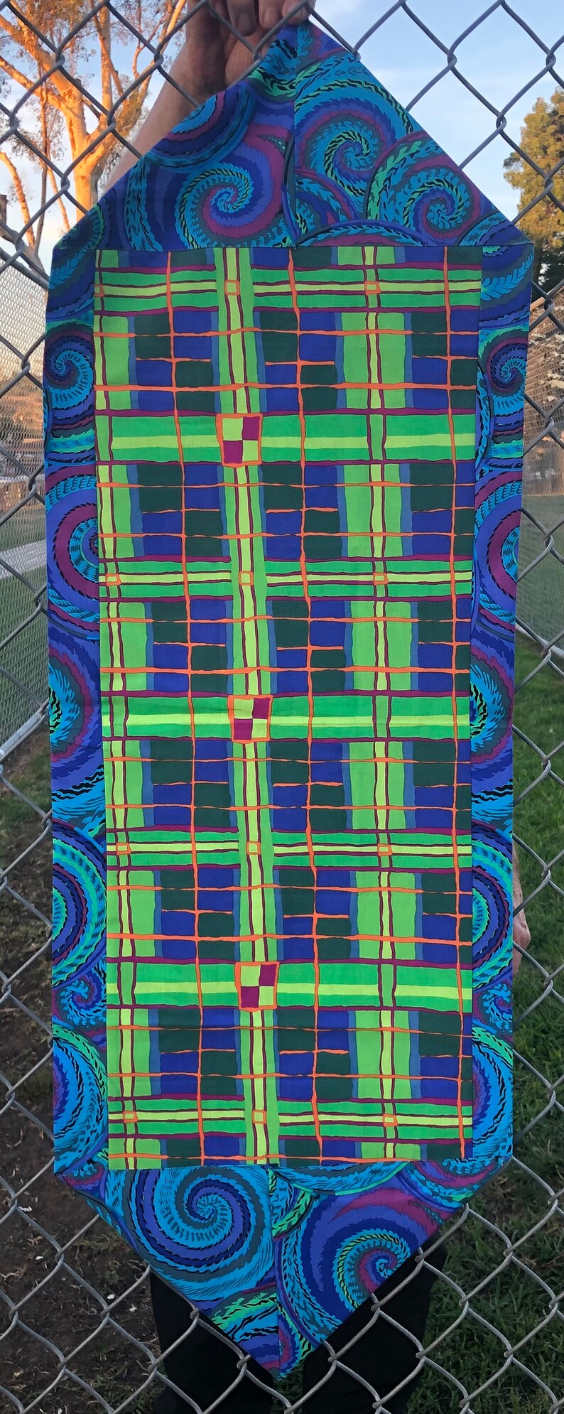 May include: A blue and green plaid fabric with a swirling blue and purple border. The fabric is made of a soft, lightweight material and is perfect for quilting, sewing, or crafting.