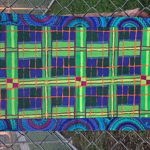 May include: A blue and green table runner with a plaid pattern and a paisley border. The runner is made of fabric and has a woven texture.