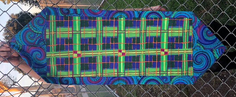 May include: A blue and green table runner with a plaid pattern and a paisley border. The runner is made of fabric and has a woven texture.