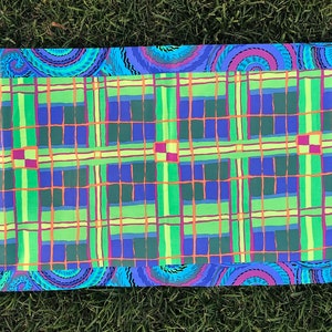 May include: A table runner with a green, blue, and yellow plaid pattern framed by a blue and purple paisley border.
