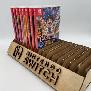 May include: A wooden Nintendo Switch game organiser holding several game cases. The organiser has the Nintendo Switch logo and text. Game cases include "Carnival Games" and "The Legend of Zelda: Breath of the Wild."