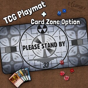May include: A gray and white playmat with a retro television test pattern design. The playmat features the text "PLEASE STAND BY" and a number "33". The playmat is designed for trading card games and includes a card zone option.