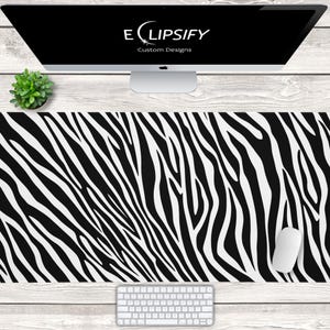 Pode incluir: Tapete de mesa com estampa de zebra em preto e branco com um teclado branco e um mouse de computador branco sobre uma superfície de madeira branca.