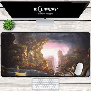 May include: A large rectangular mousepad featuring a landscape painting with a boat on the water. The painting depicts a cave with a pink and purple sky. A computer monitor with the text "ELIPSIFY Custom Designs" is above the mousepad.