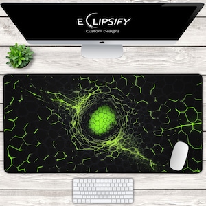 Op de afbeelding: Zwart en groene gaming muismat met een zeshoekig patroon en een centraal groen vortex ontwerp. De muismat heeft de tekst "ELIPSIFY Custom Designs" bovenaan. Een witte muis en toetsenbord zijn ook zichtbaar.
