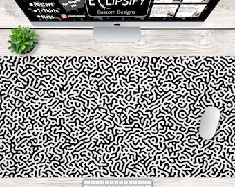 Puede incluir: Alfombrilla de ratón de diseño abstracto en blanco y negro con fondo blanco y líneas negras que forman un patrón de laberinto. La alfombrilla de ratón está sobre una superficie de madera clara con un teclado blanco y un ratón de ordenador blanco.