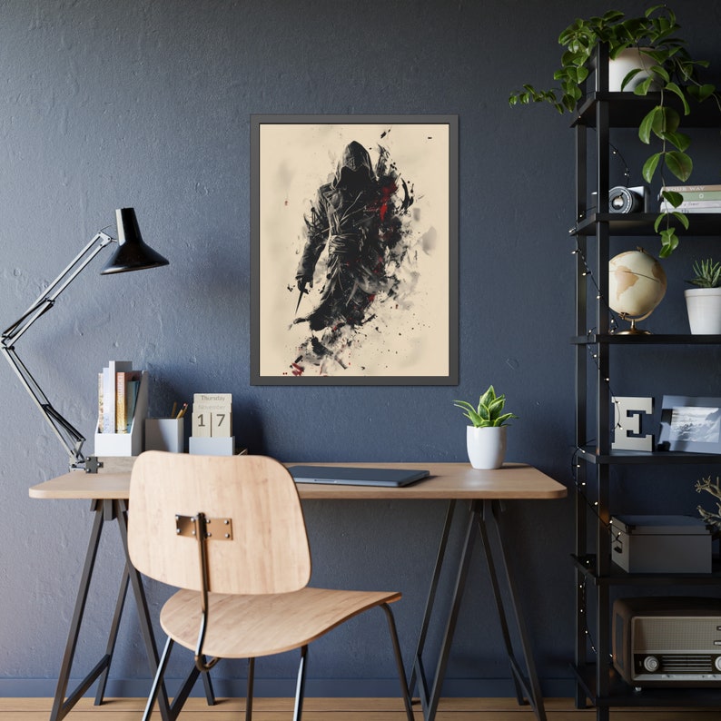 May include: Framed art print featuring a stylized figure in a hooded cloak, holding a blade. The artwork uses a black, white, and red color palette with a watercolor effect. The print is displayed on a desk with a black lamp and a wooden chair.