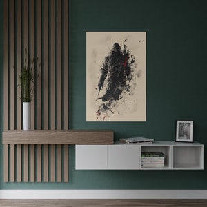 May include: A framed art print featuring a stylized figure in a hooded cloak, holding a blade. The artwork uses a black, white, and red color palette with a watercolor effect. The print is displayed on a wall above a modern white and wood-tone shelf.