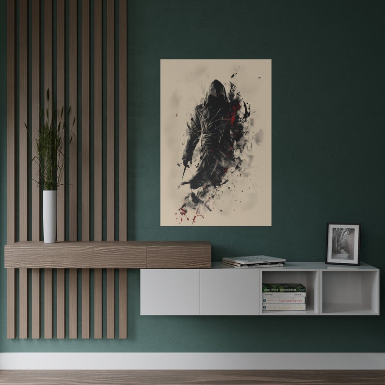 May include: A framed art print featuring a stylized figure in a hooded cloak, holding a blade. The artwork uses a black, white, and red color palette with a watercolor effect. The print is displayed on a wall above a modern white and wood-tone shelf.