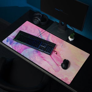 May include: A pink and white gaming mouse pad with a colorful keyboard and a mouse. The mouse pad features a stylized illustration of a dragon with pink and purple hues.