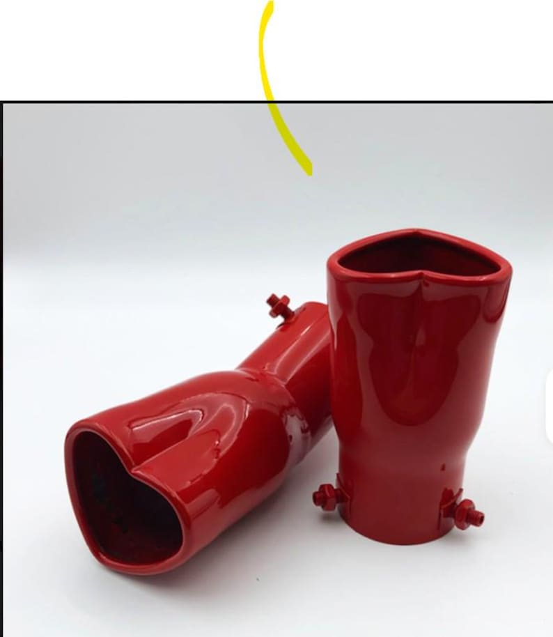 May include: Two red exhaust tips with a heart-shaped opening. The tips are made of a glossy material and have mounting hardware. One tip is lying on its side, while the other stands upright.
