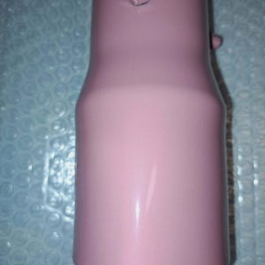 May include: A pink metal component with a cylindrical shape, featuring a threaded fitting and a small protruding detail. The object has a smooth, painted finish and a slight taper in its design.