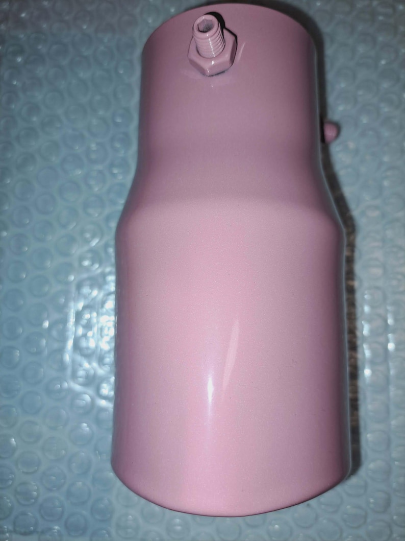May include: A pink metal component with a cylindrical shape, featuring a threaded fitting and a small protruding detail. The object has a smooth, painted finish and a slight taper in its design.