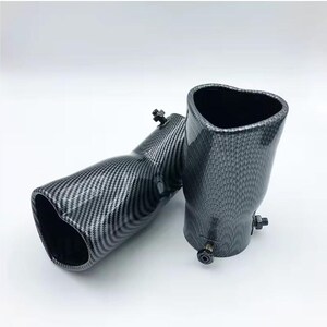 May include: Two carbon fiber exhaust tips with a heart-shaped opening. The tips have a black and gray checkered pattern and are angled. Each tip has a bolt for attachment. The background is white.