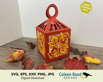 May include: A red paper lantern with a handle, featuring cut-out yellow maple leaves. The lantern is surrounded by fallen leaves in shades of red, yellow, and brown. The image includes the text "Digital Download File!" and "SVG, EPS, DXF, PNG, JPG Digital Download Coleen Rood DESIGNS."
