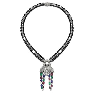 May include: A necklace featuring a chain of black rectangular links accented with small white diamonds. The central pendant is composed of white metal set with diamonds, featuring two dangling tassels of multi-colored gemstones including red, blue, and green.