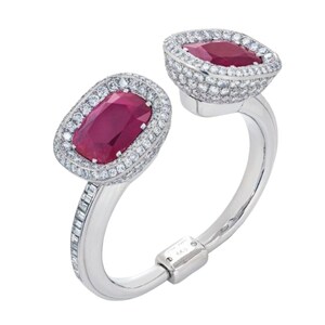 Op de afbeelding: Een zilveren armband met twee ovale robijn edelstenen gezet in een halo van diamanten. De armband heeft een scharnierende sluiting.