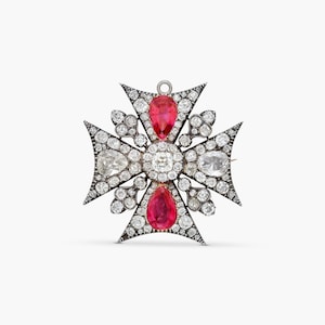 Puede incluir: Un broche en forma de cruz con un diamante redondo central rodeado de diamantes más pequeños. Dos piedras preciosas rojas en forma de pera están colocadas verticalmente, mientras que dos diamantes en forma de pera están colocados horizontalmente.