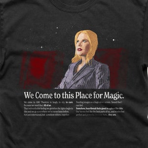 May include: A black t-shirt featuring a quote about the magic of going to the cinema. The quote reads "We Come to this Place for Magic." and is accompanied by a picture of a woman looking up at a starry sky.