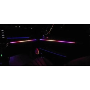 May include: A close-up of a car interior with a strip of LED lights that are illuminated in blue, white, and pink.