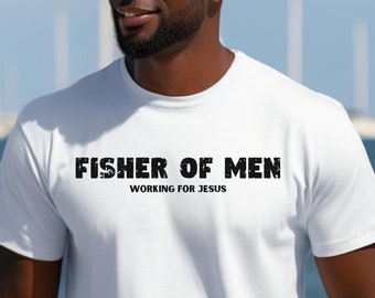 May include: White t-shirt with black text that reads "Fisher of Men Working for Jesus". The person wearing the shirt is standing in front of a body of water with boats in the background.