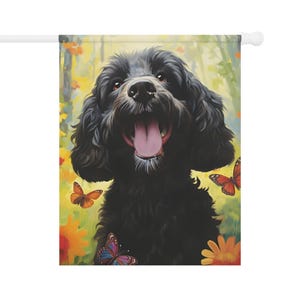 Puede incluir: Una bandera de jardín decorativa con un perro negro sonriente con la lengua fuera. El perro está rodeado de mariposas y flores coloridas sobre un fondo suave amarillo y verde. La bandera está montada en un mástil blanco.