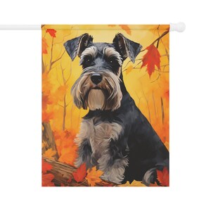 Puede incluir: Un perro Schnauzer miniatura negro y plateado sentado en un tronco en un entorno de bosque de otoño. El perro está rodeado de hojas naranjas, amarillas y rojas.