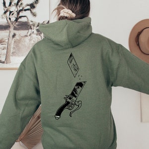 May include: A green hooded sweatshirt with a black and white graphic print of a sword and a manga-style face on the back.