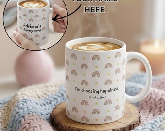 Könnte beinhalten: Weiße Keramik-Tasse mit Henkel, verziert mit Regenbögen und Sternen. Auf der Tasse steht der Text "I'm choosing happiness (and coffee)". Die Tasse steht auf einem Holzuntersetzer.
