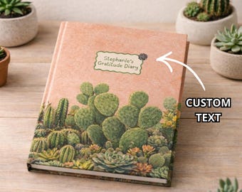 Könnte beinhalten: Ein Hardcover-Journal mit Kaktus- und Sukkulenten-Design. Das Cover ist pfirsichfarben mit einer grün-braunen Illustration verschiedener Kakteen. Der Text "Stephanie's Gratitude Diary" ist auf einem Etikett auf dem Cover aufgedruckt.