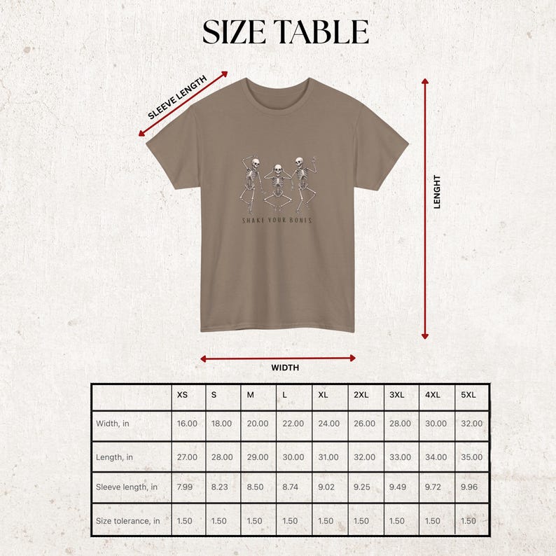 May include: A tan t-shirt featuring a graphic of three dancing skeletons and the text "Shake Your Bones." The image includes a size table with measurements in inches for width, length, and sleeve length.