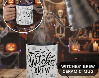 Könnte beinhalten: Eine weiße Keramiktasse mit dem Text "Witches' Brew" in schwarzer Schrift, verziert mit Fledermäusen, Kristallen und anderen mystischen Symbolen. Die Tasse hat eine schwarze Innenseite und wird mit heißer Flüssigkeit gefüllt.