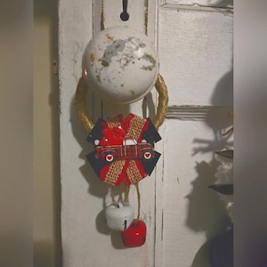 Puede incluir: Una corona rústica con un camión rojo y negro que lleva corazones, un lazo de arpillera y tres campanas blancas colgando.