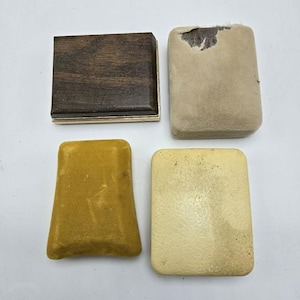 May include: Four empty jewelry boxes. Two are brown with a gold trim, one is yellow velvet, and one is beige.