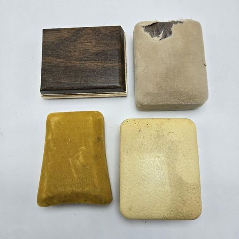 May include: Four empty jewelry boxes. Two are brown with a gold trim, one is yellow velvet, and one is beige.