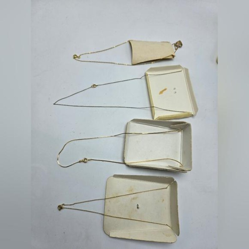 May include: Four gold chains on white cardboard backing. The chains are different lengths and are displayed in a vertical stack.