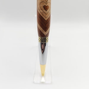 May include: A wooden pen with a heart design and a gold and silver metal trim.