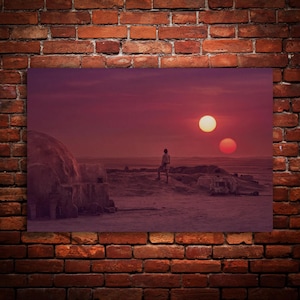 Può includere: Una stampa artistica rettangolare da parete che raffigura un paesaggio desertico al tramonto con due soli in un cielo rosso intenso. Una figura solitaria si trova su una duna rocciosa vicino a una struttura a cupola.