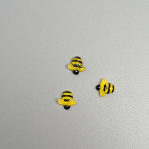 May include: Three small yellow and black bee figurines. The bees are made of glass and have a glossy finish.