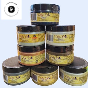 May include: A collection of Dixie Belle Glaze paint jars in various colors, including black, silver, whitewash, copper bronze, and gold shimmer. Each jar is 4 fl oz (118 ml) and has a black lid. The jars are stacked on a light blue background.