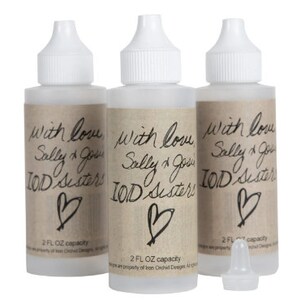 May include: Three clear plastic bottles with white caps, each containing a liquid. The bottles have brown labels with the text "with love Sally & Go IOD Sisters" and a heart symbol. Each bottle has a 2 fl oz capacity.