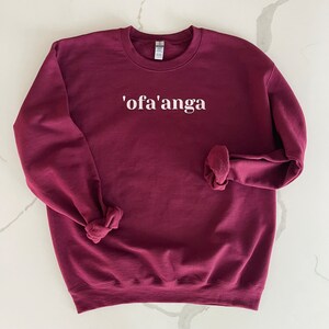 May include: A maroon sweatshirt with the text "'ofa'anga" printed in white on the front.