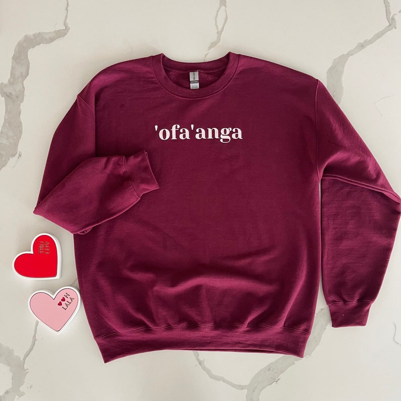 May include: A maroon sweatshirt with the text 'ofa'anga' printed in white on the front.